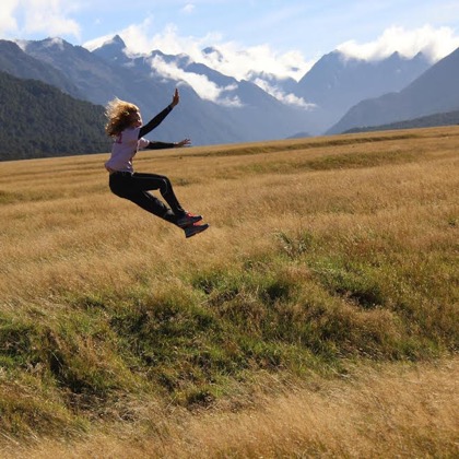 A mountain view background with a student jumping in the fields