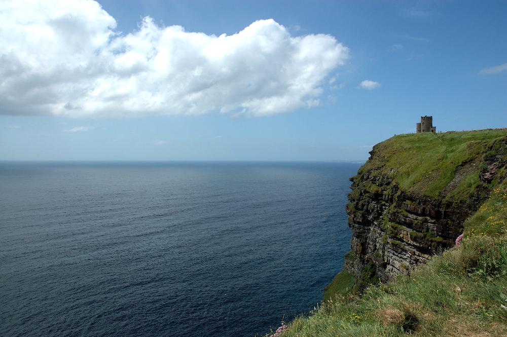 A castle on a grassy cliff overlooking a blue sea